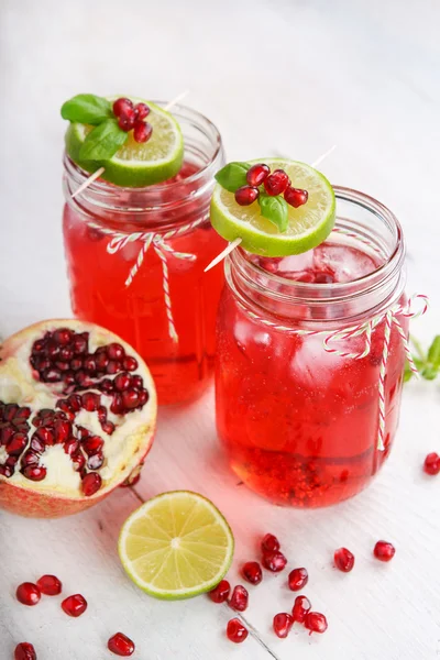 Twee glazen met rode pomgranate SAP, limoen en munt. — Stockfoto
