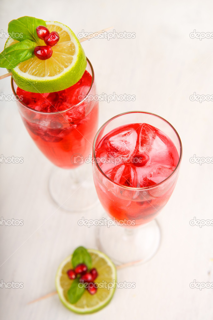 Two glasses with red pomgranate champagne, lime and mint.