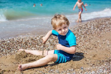 kum ve taşların oynayan küçük yürümeye başlayan çocuk sahilde