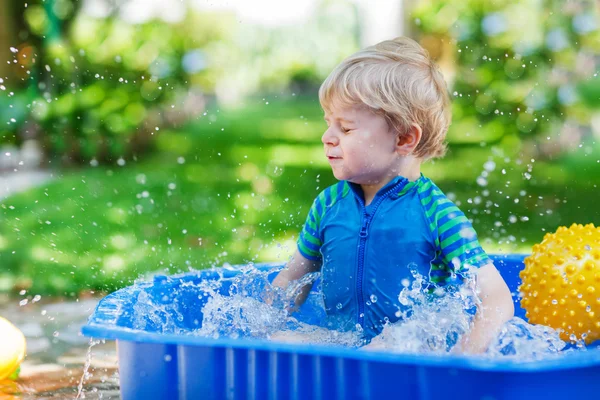 Kleine peuter jongen met plezier met opspattend water in zomer gar — Stockfoto