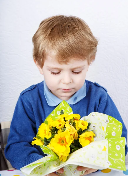 Cute lovely toddler boy of 3 years sniffing yellow flowers for m — Stock Photo, Image