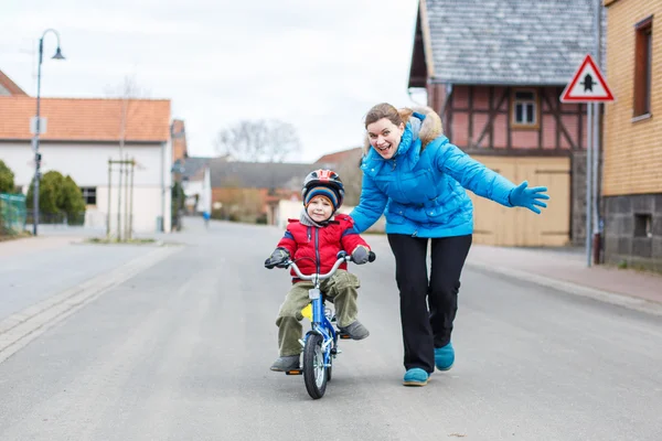 Joven madre enseñando a su hijo pequeño de 3 años a montar en bicicleta —  Fotos de Stock
