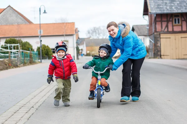 彼女の 2 年を教える若い母親古いの幼い息子、自転車に乗る — ストック写真