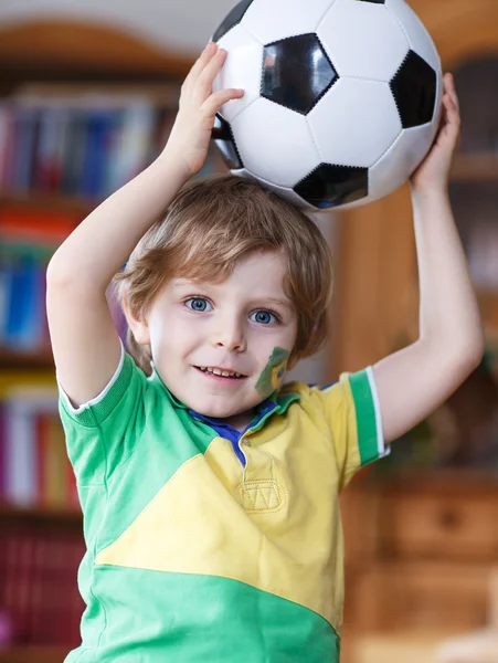 Liten blond förskola pojke på 4 år med fotboll ser fot — Stockfoto