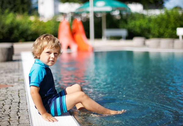 Lindo niño jugando con agua junto a la piscina al aire libre — Foto de Stock