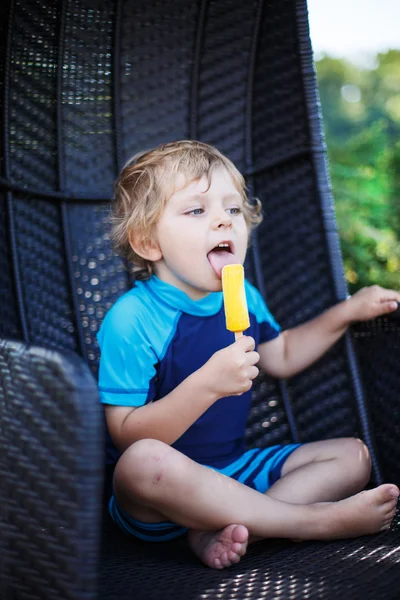 Little blond boy eating yellow ice cream — Stock Photo, Image