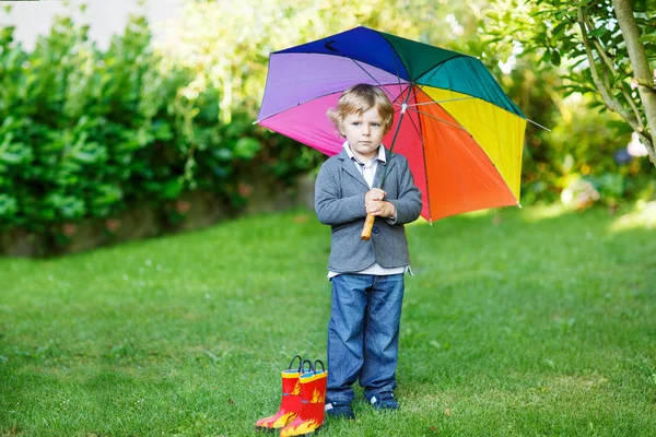 Pequeno menino bonito da criança com guarda-chuva colorido e botas, outdoo — Fotografia de Stock