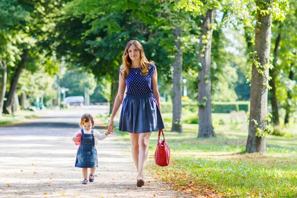 Jovem mulher e menina de um ano andando através do verão p — Fotografia de Stock