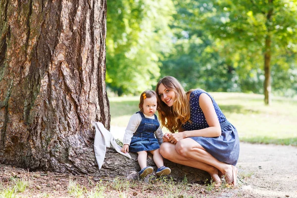 Young woman and little girl of one year walking through summer p — Stock Photo, Image