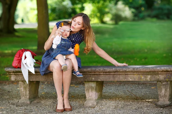 Beautiful mother and little daughter walking in summer park — Stock Photo, Image