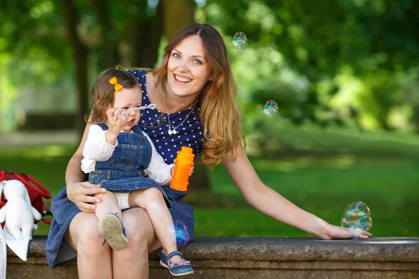 Beautiful mother and little daughter walking in summer park — Stock Photo, Image