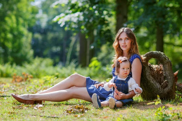 Beautiful mother and little daughter walking in summer park — Stock Photo, Image