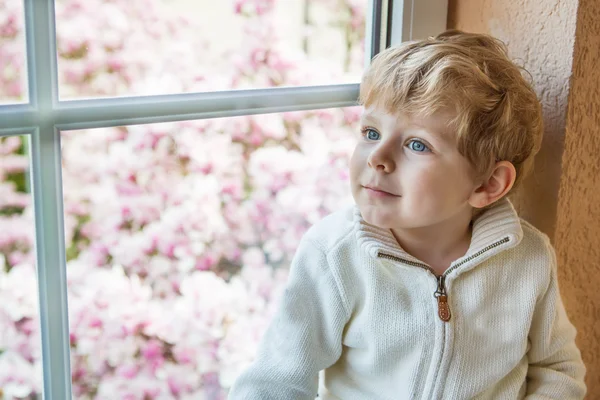 Bedårande barn pojke tittar ut genom fönstret — Stockfoto