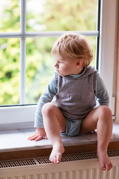 Çok güzel yürümeye başlayan çocuk pencereden dışarı bakıyor — Stok fotoğraf