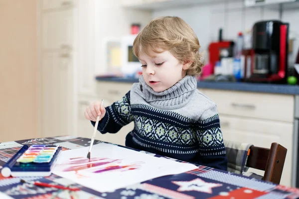Adorável criança menino se divertindo interior, pintura com diferentes — Fotografia de Stock