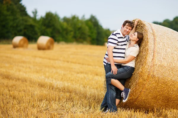 Giovane coppia innamorata sul campo di fieno giallo la sera d'estate . — Foto Stock