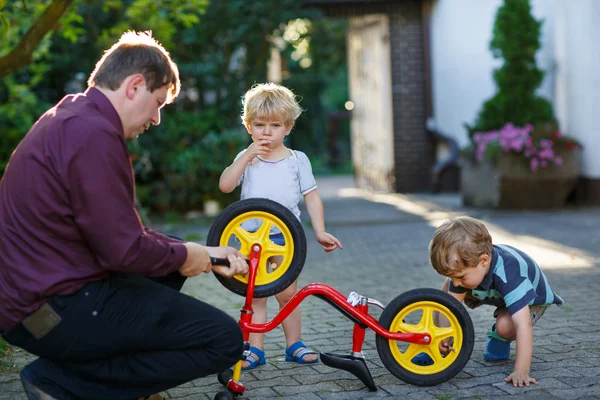 Retrato de dos chicos lindos reparando rueda de bicicleta con padre ou — Foto de Stock