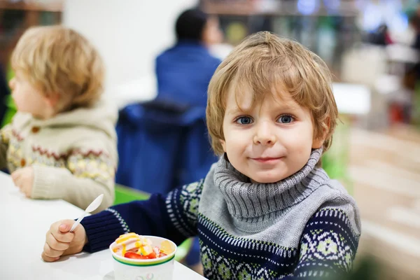 Little blond toddler boy eating ice cream iin shopping mall — Stock Photo, Image