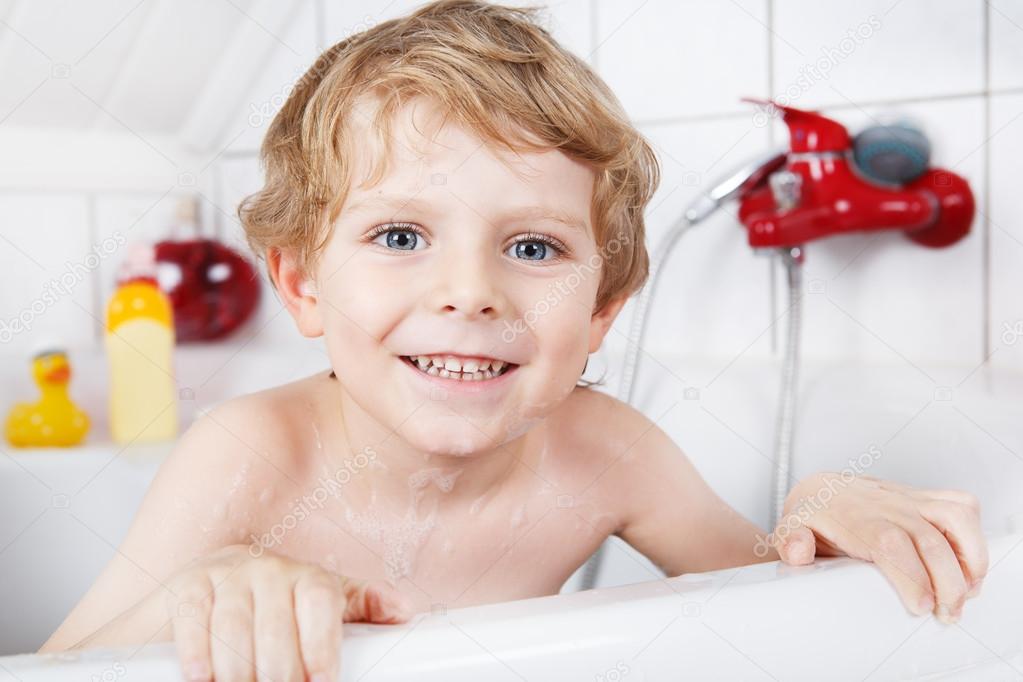 Cute little toddler boy of two years having fun by taking bath i