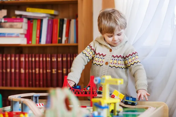 Малыш играет с деревянной железной дорогой, в помещении — стоковое фото