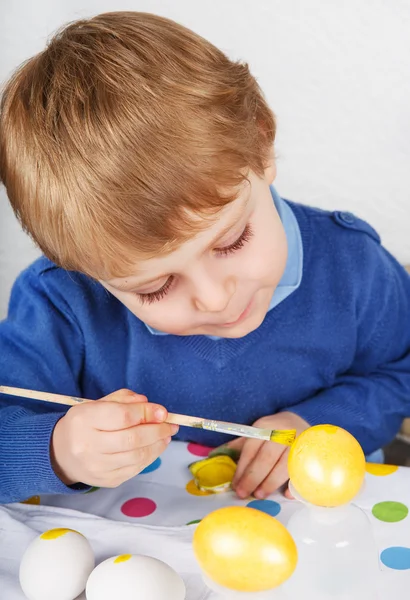 Menino pequeno pintando ovos coloridos para caça à Páscoa — Fotografia de Stock