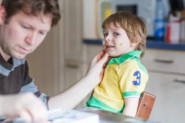 Father painting flag on face of little son — Stock Photo, Image