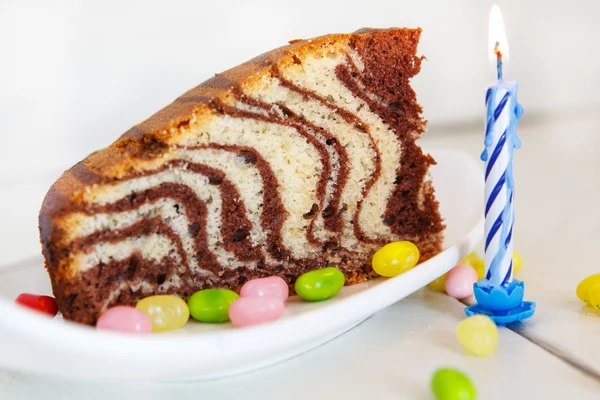 Pastel de cumpleaños con chocolate y una vela azul . — Foto de Stock