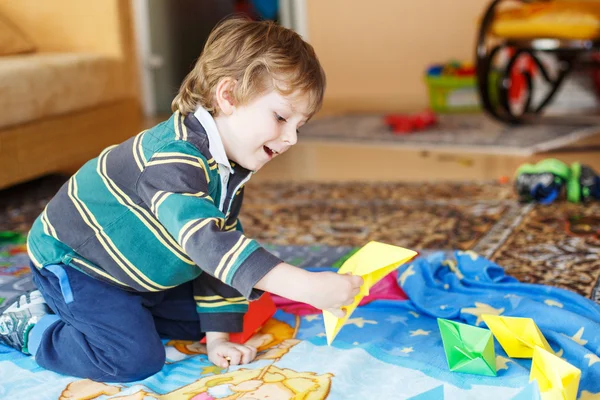 Funny boy of 4 years playing with paper ships at home — Stock Photo, Image