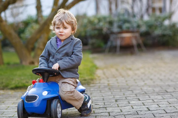 Menino dirigindo carro de brinquedo grande, ao ar livre — Fotografia de Stock