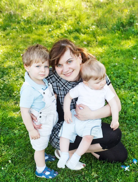 Glückliche dreiköpfige kaukasische Familie: junge Mutter und zwei kleine Geschwister — Stockfoto