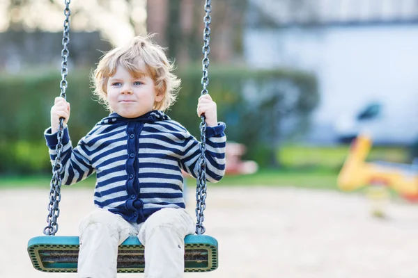 Adorabile bambino ragazzo avendo divertente catena swing su all'aperto playgroun — Foto Stock