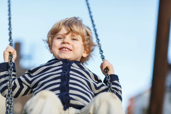 Entzückende Kleinkind Junge mit Spaß Kettenschaukel auf Outdoor-Spielplatz — Stockfoto