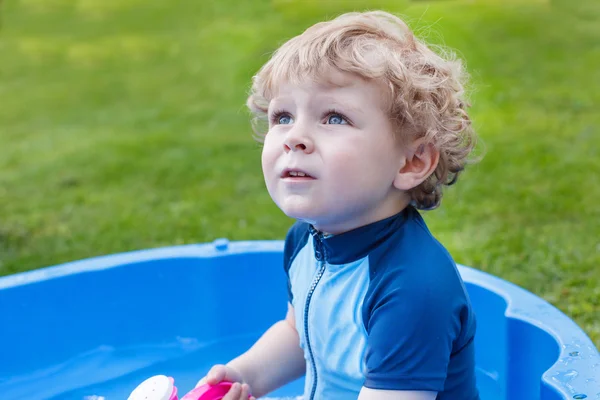 Su ile dışarıda oynarken sevimli sarışın yürümeye başlayan çocuk. — Stok fotoğraf