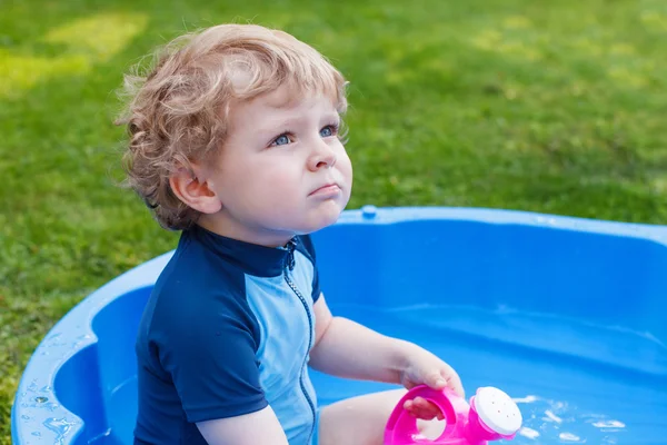 Schattige blonde peuter jongen spelen met water, buitenshuis. — Stockfoto