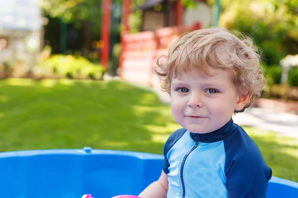 Toddler biały blond chłopiec bawi się wody na zewnątrz. — Zdjęcie stockowe