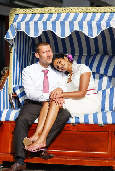 Beautiful indian bride and caucasian groom, in beach chair. — Stock Photo, Image