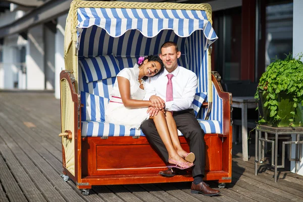 Beautiful indian bride and caucasian groom, in beach chair. — Stock Photo, Image