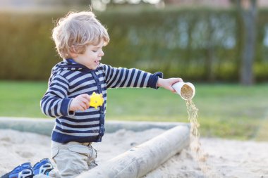 Açık sahada kum ile eğlenmek çok güzel yürümeye başlayan çocuk