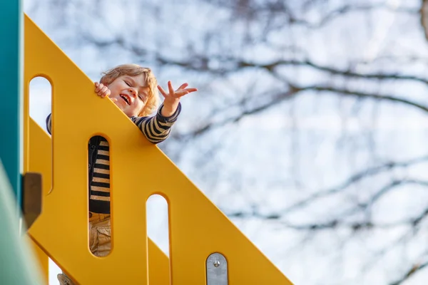 Adorável criança menino se divertindo e deslizando no playgroun ao ar livre — Fotografia de Stock