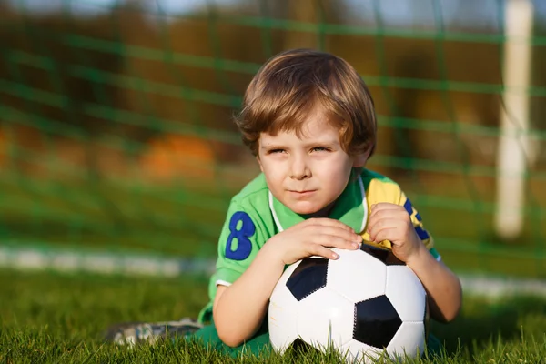 Blond boy of 4 playing soccer with football on football field — Stock Photo, Image
