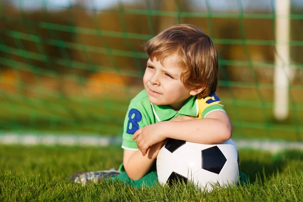 Niño rubio de 4 jugando al fútbol con el fútbol en el campo de fútbol —  Fotos de Stock