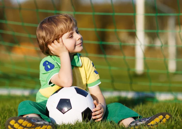 Garçon blond de 4 ans jouant au football avec le football sur le terrain de football — Photo