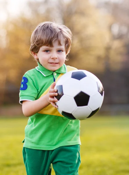 Блондин 4 лет играет в футбол с футболом на футбольном поле — стоковое фото