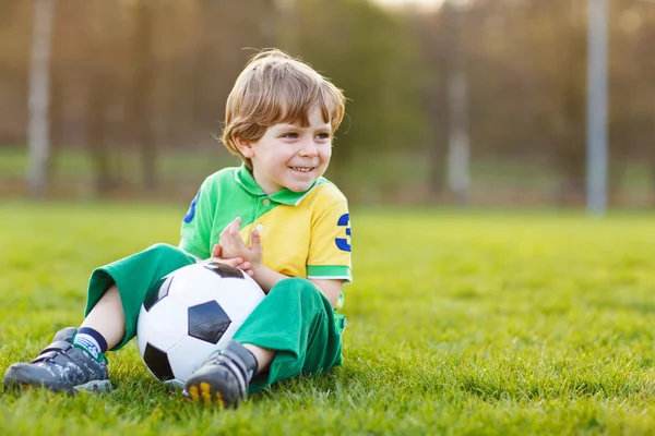 Blond boy of 4 playing soccer with football on football field — Stock Photo, Image