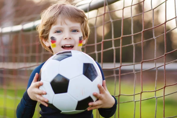 Blond boy of 4 playing soccer with football on football field — Stock Photo, Image