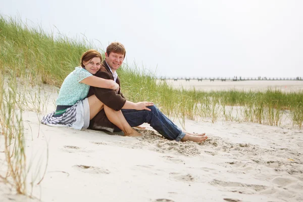 Unga lyckliga paret älskar att ha kul på sanddynerna vid stranden — Stockfoto