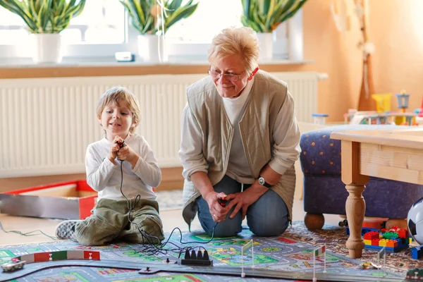 Grootmoeder en weinig kleinzoon spelen met racewagens — Stockfoto