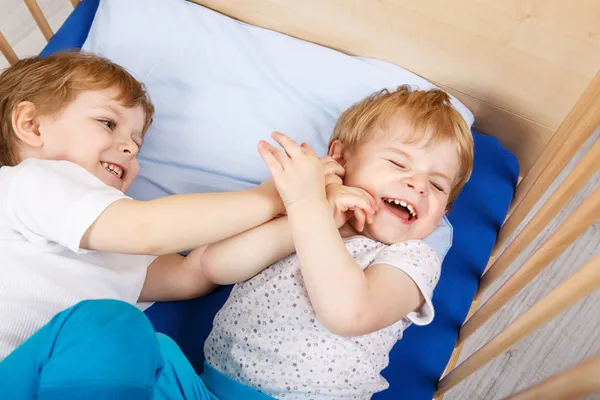 Små syskon pojkar har roligt i sängen hemma — Stockfoto