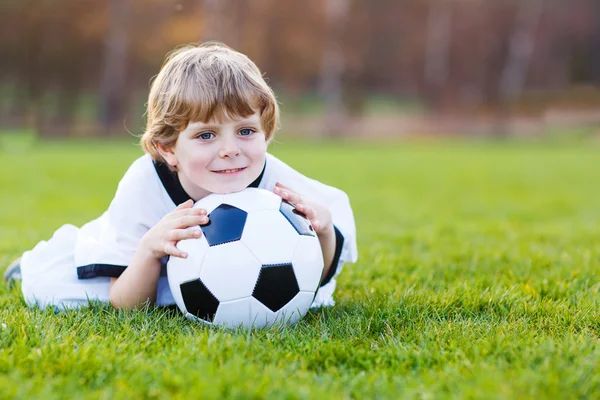 Loira menino de 4 jogando futebol com futebol no campo de futebol — Fotografia de Stock
