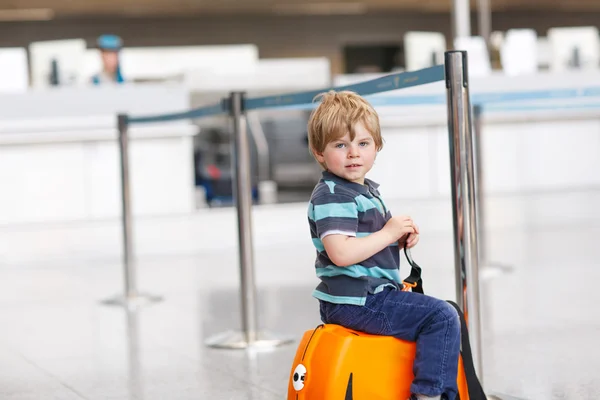 Маленький мальчик собирается в отпуск поездку с чемоданом в аэропорту — стоковое фото